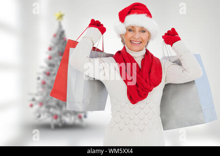 Woman holding shopping bags festive contre l'arbre de Noël dans la salle floue Banque D'Images