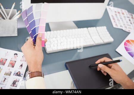 Designer travaillant au bureau à l'aide d'échantillon de couleur et de la tablette dans son bureau Banque D'Images