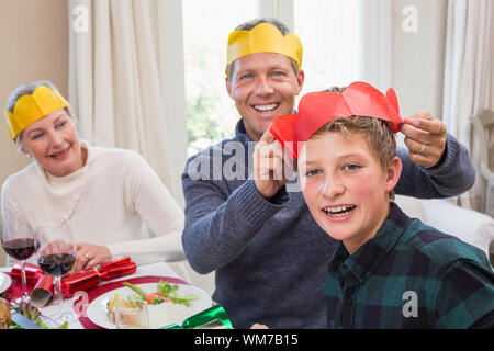 Smiling father putting party hat sur fils chef à domicile dans la salle de séjour Banque D'Images