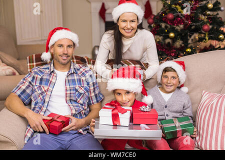 Jolie famille posant avec des dons de Noël à la maison dans le salon Banque D'Images