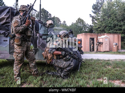 Un soldat de la troupe C, 1er Escadron, 75e Régiment de cavalerie, 2e Brigade Combat Team et un béret vert se mettre à couvert derrière un véhicule au cours d'un exercice conjoint sur Fort Campbell, mercredi 16 août, 2019. Les soldats ont passé deux semaines de formation avec les Bérets verts du 5e Groupe des forces spéciales (Airborne), sur des exercices de combat, la manipulation des prisonniers de guerre, des soins aux blessés et l'évacuation des tactiques, et la planification de la mission. (U.S. Photo de l'armée par le sergent. Iman Broady-Chin) Banque D'Images