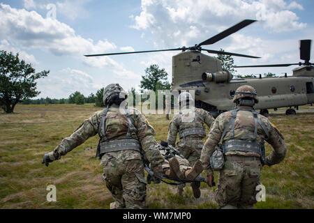 La Garde Nationale de New York les médecins affectés au siège de la batterie du 1er Bataillon, 258e de conduite d'artillerie de formation pendant un exercice d'évacuation avec les équipages d'hélicoptère CH-47 Chinook de la Compagnie B, 3e Bataillon, 126e au cours de l'Aviation les deux formations annuelles des unités à Fort Drum, N.Y., 29 juillet 2019. U.S. Army National Guard photo par le Sgt. Matthieu Gunther. Banque D'Images