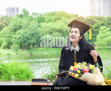 Belle asiatique femmes diplômées holding diploma avec fierté et sourire dans les toges.Félicitation bonheur female student wearing graduation Banque D'Images