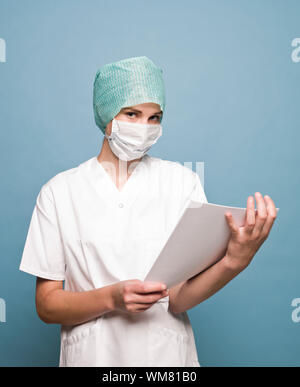 Infirmière avec un masque chirurgical et un journal face à l'appareil photo Banque D'Images