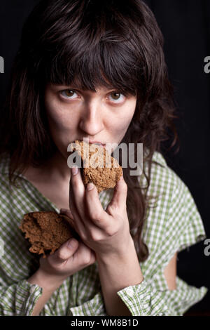 Portrait d'un pauvre mendiant femme mangeant du pain dans ses mains Banque D'Images