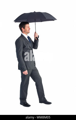 Businessman s'abritant sous parapluie noir sur fond blanc Banque D'Images