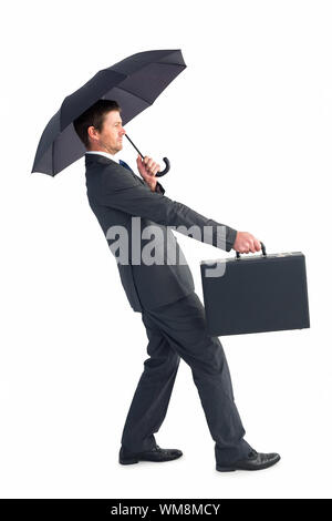 Businessman s'abritant sous parapluie noir sur fond blanc Banque D'Images