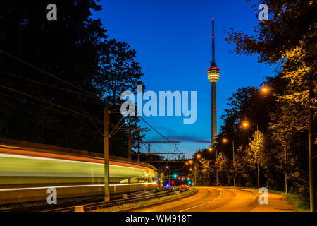 L'Allemagne, des veilleuses de Stuttgart City tandis qu'un train est en passant la vue sur la tour de télévision allumé par bâtiment nuit dans Twilight Banque D'Images
