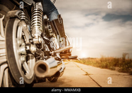Biker girl riding sur une moto. Vue du bas des jambes dans des bottes de cuir. Banque D'Images