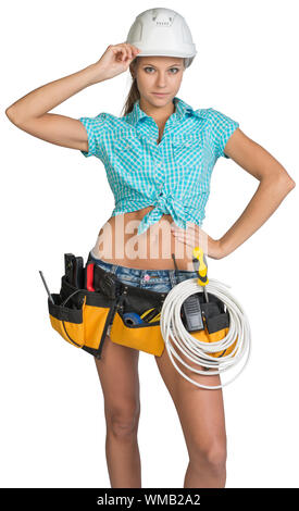 Woman wearing hard hat et ceinture d'outils, avec la bobine de câble au niveau de sa taille, sa main à la loi, looking at camera. Isolé sur fond blanc Banque D'Images