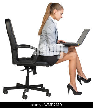 Vertical sur le bord de chaise de bureau, avec un ordinateur portable sur ses genoux. regarder l'écran. Plus isolé sur fond blanc Banque D'Images