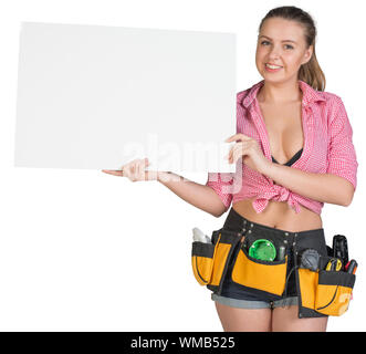 Femme en ceinture d'outils montrant blanc bannière, looking at camera, souriant. Isolé sur fond blanc Banque D'Images