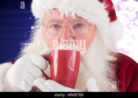 Des boissons d'un père noël tasse rouge contre la lumière chatoyante de conception sur purple Banque D'Images