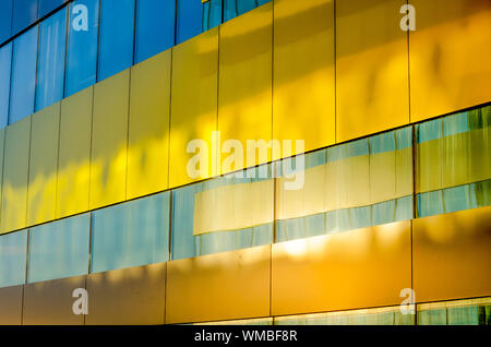 Façade en verre coloré d'un immeuble moderne dans le centre d'une ville avec des motifs de lumière et rayons de soleil Banque D'Images