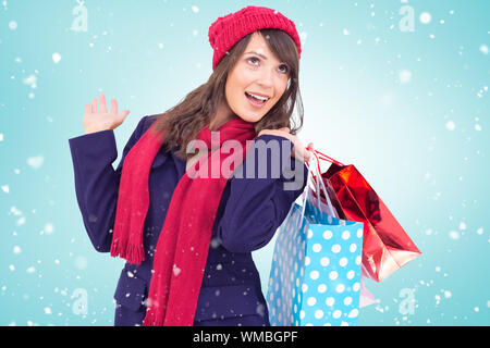 Happy brunette in winter clothes holding shopping bags contre vignette bleue Banque D'Images