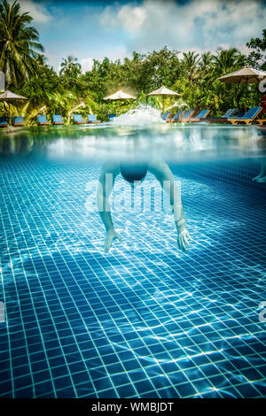 L'homme plonge dans une piscine donne sur l'eau et sous l'eau. Les Maldives. Banque D'Images