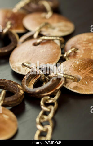 Rayé et terni vieux bijoux argent avec deux disques plats encadrant un anneau suspendu sur un ovale lien chaîne, plan rapproché sur un fond gris Banque D'Images