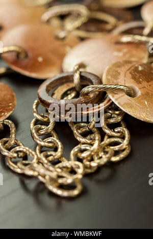 Rayé et terni vieux bijoux argent avec deux disques plats encadrant un anneau suspendu sur un ovale lien chaîne, plan rapproché sur un fond gris Banque D'Images