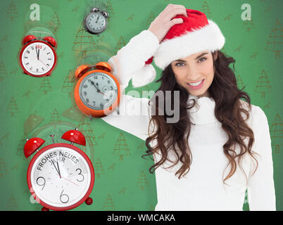 Confus brunette in santa hat contre green modèle d'arbre de Noël Banque D'Images