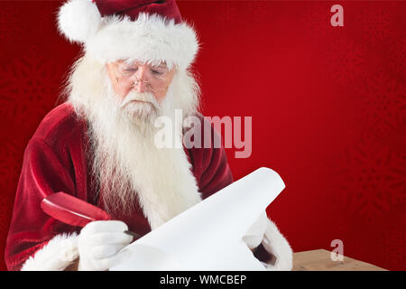 Santa écrit quelque chose avec une plume contre fond rouge Banque D'Images