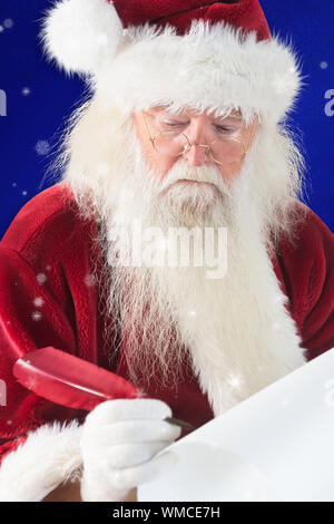 Santa écrit quelque chose avec une plume contre blue snowflake background Banque D'Images
