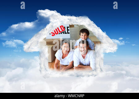 Famille dans leur nouvelle maison située sur le plancher avec des cases contre ciel bleu avec des nuages Banque D'Images