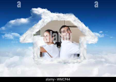Couple avec Radiant unpacking boxes moving dans une nouvelle maison contre ciel bleu avec des nuages Banque D'Images