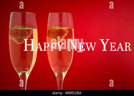 Bonne année contre deux verres de champagne avec des fraises Banque D'Images