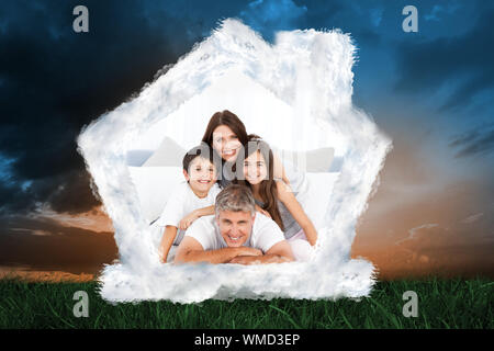 Famille heureuse regardant la caméra contre l'herbe verte sous le ciel bleu et orange Banque D'Images