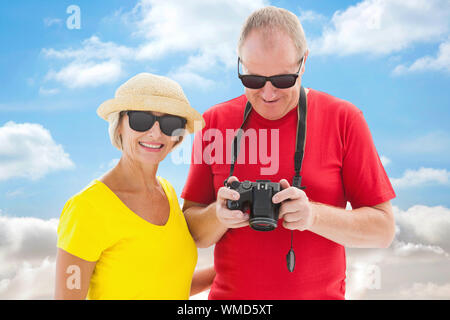 Mature Woman wearing sunglasses against cloudy sky Banque D'Images