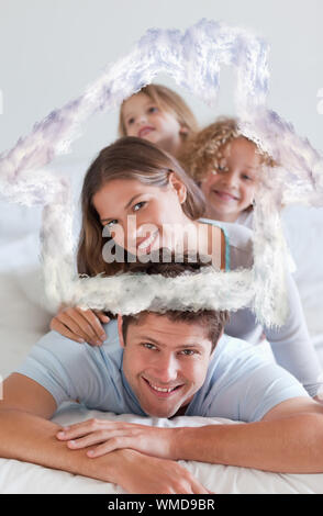 Portrait d'une famille heureuse étendu sur chaque autre contre chambre contours dans les nuages Banque D'Images