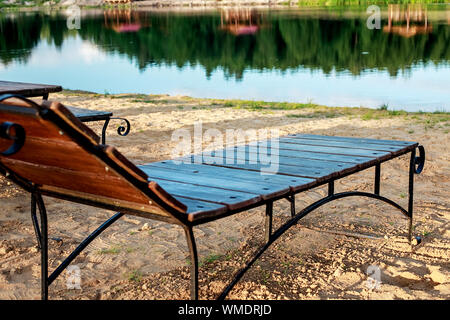 Zone de détente. Des chaises longues et des chaises en bois avec des tables sur la plage au bord du lac, face au lac. Bélarus Banque D'Images