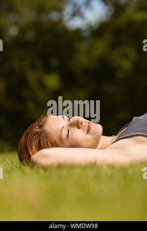 Jolie rousse couché avec les yeux fermés en position de stationnement au soleil Banque D'Images