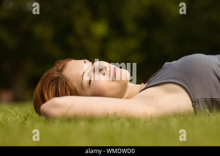 Jolie rousse couché avec les yeux fermés en position de stationnement au soleil Banque D'Images