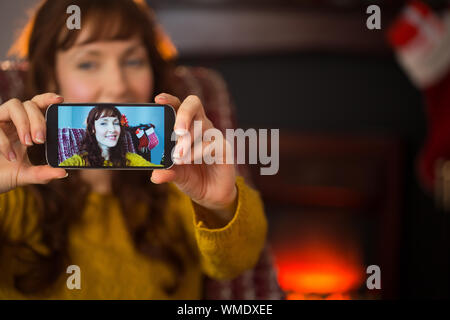 Jolie rousse prenant une à selfies Noël à la maison dans le salon Banque D'Images