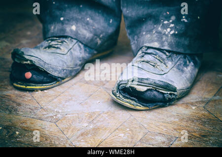 Vieilles bottes déchirées sur les pieds de l'homme. Bottes avec des trous. Selective focus Banque D'Images