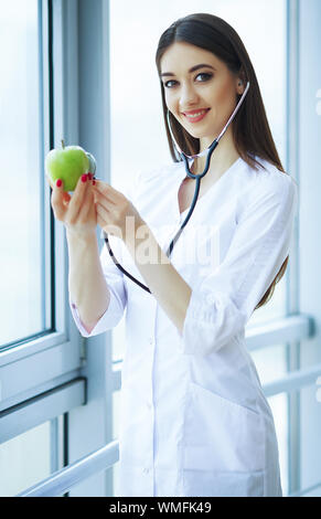 Santé et beauté. La diététiste tient les fruits et légumes frais dans les mains. Jeune docteur avec un beau sourire. Haute résolution Banque D'Images