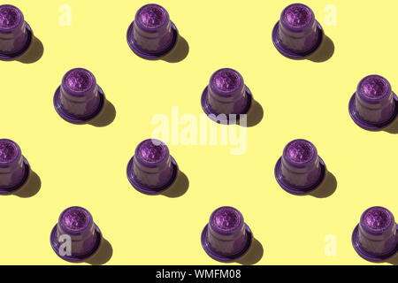Motif coloré violet et jaune de capsules de café expresso sur fond pastel, vue du dessus Banque D'Images