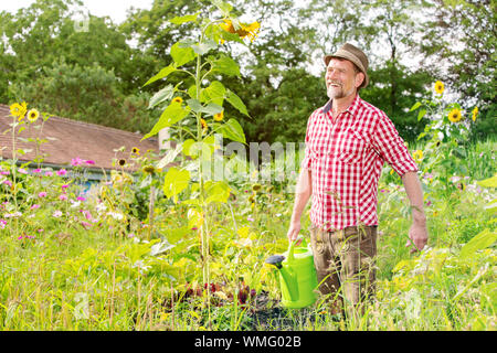 Portrait of handsome man standing bavarois dans le jardin et arrosage des fleurs Banque D'Images