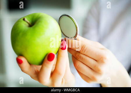 La santé. L'alimentation saine. La nutritionniste tient dans les mains de frais vert pomme. Les fruits et légumes frais sur la table. Heureux Médecin. Haut Banque D'Images
