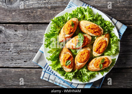 Vue de dessus de la bruschetta grillé avec purée de légumes, purée, caviar de courgettes cuites, tomate, carotte et épices servi sur une plaque blanche sur un bois Banque D'Images