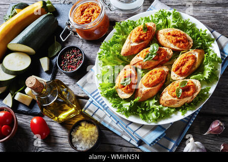 Baguette grillées avec purée de légumes, purée, caviar de courgettes cuites, tomate, carotte et épices servi sur une plaque blanche sur une table en bois rustique wit Banque D'Images