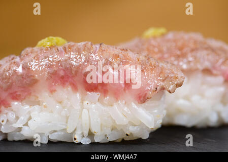 Nigiri de chaleur-gravé kobé habillés avec de la moutarde, servis sur une plaque d'ardoise, carrés détails macro Banque D'Images