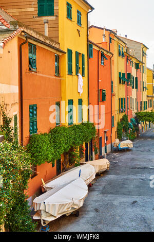 Rue avec maisons de couleur jaune et orange dans le quartier Boccadasse, à Gênes avec les bateaux de pêche garé, Italie Banque D'Images