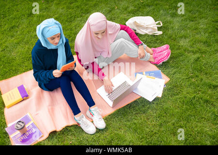 Les étudiants musulmans assis dehors près de l'université et étudier Banque D'Images