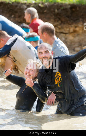 Un couple négocier la 'Mud Mile' obstacle à la dure épreuve d'endurance en Badminton Mudder Park, Gloucestershire UK Banque D'Images