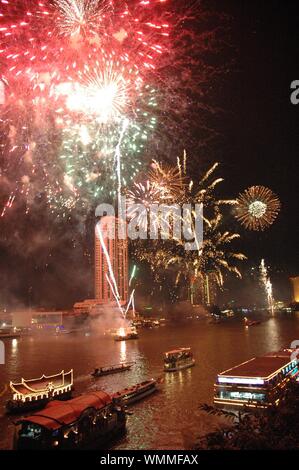 feux d'artifice éclatant dans le ciel près des bâtiments près du corps d'eau avec des bateaux sur son corps Banque D'Images