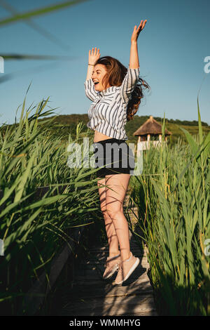 Belle jeune fille portant une chemise rayée, sauter et passer un bon moment, à Reed National Reservation, SIC Village, Roumanie Banque D'Images