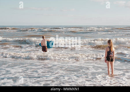 Jeune garçon et fille à jouer dans les vagues à la plage