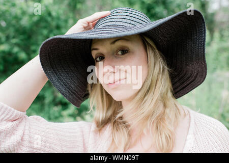 Portrait d'une femme debout regardant la caméra smiling with a hat Banque D'Images